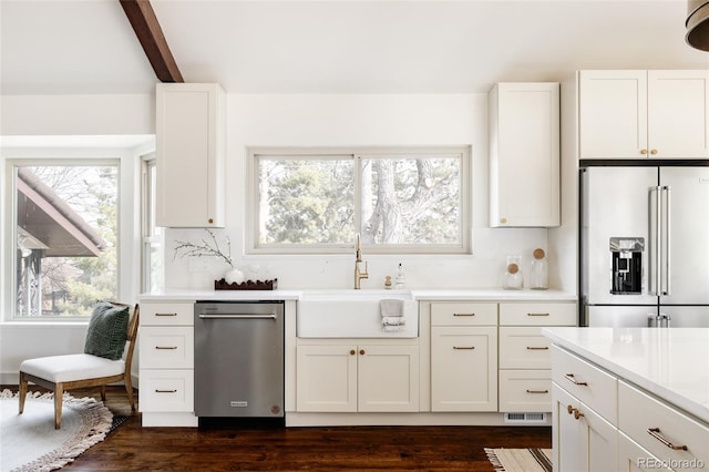 kitchen featuring stainless steel appliances, a sink, white cabinets, light countertops, and decorative backsplash