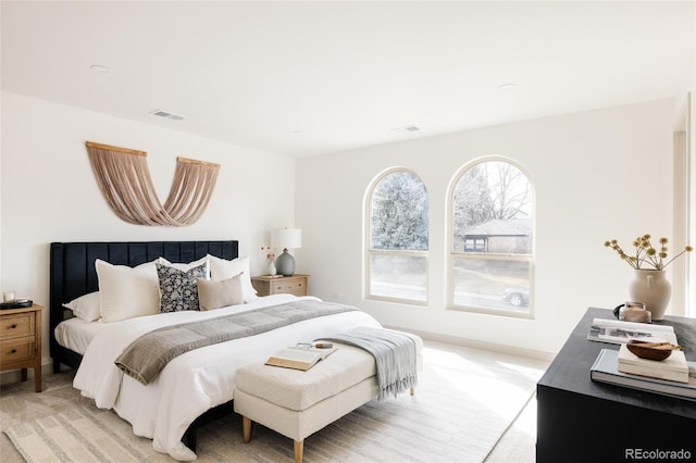 bedroom with baseboards, visible vents, and light colored carpet