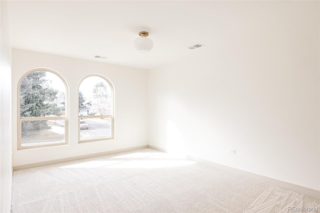 spare room with carpet, visible vents, and baseboards