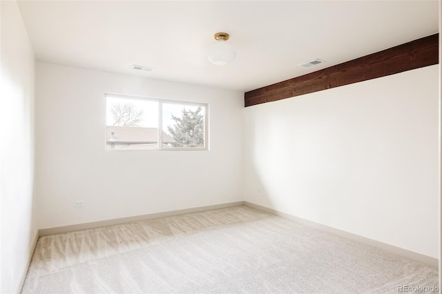 empty room with carpet, visible vents, and baseboards