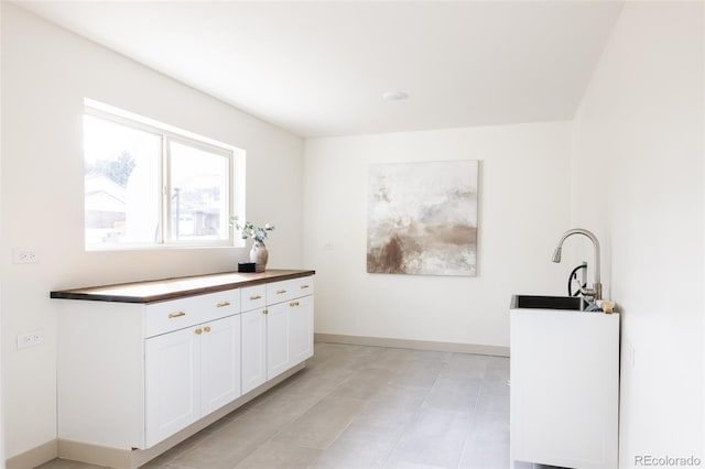 interior space with baseboards, a sink, and white cabinets