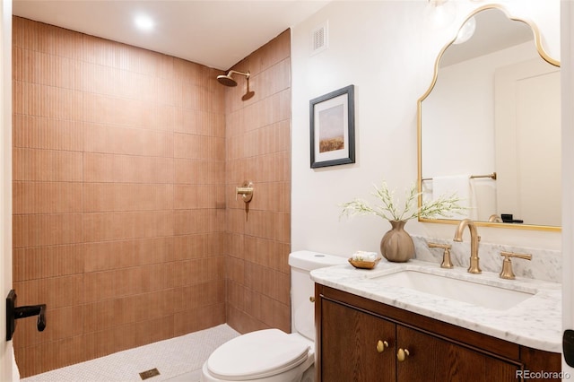 full bathroom with toilet, visible vents, tiled shower, and vanity