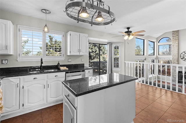 kitchen with a center island, white cabinetry, a sink, dishwasher, and dark tile patterned floors