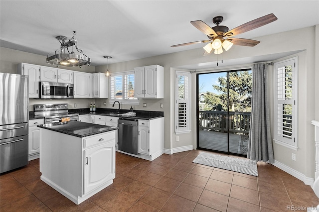 kitchen featuring appliances with stainless steel finishes, dark countertops, white cabinets, and a sink