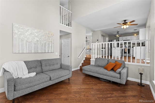 living area with baseboards, ceiling fan, stairway, and wood finished floors