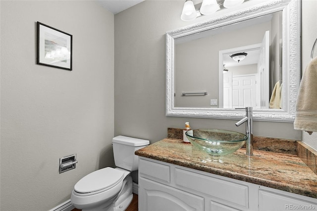 bathroom featuring toilet, a baseboard heating unit, and vanity