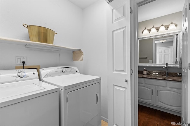 clothes washing area featuring laundry area, dark wood-style flooring, independent washer and dryer, and a sink