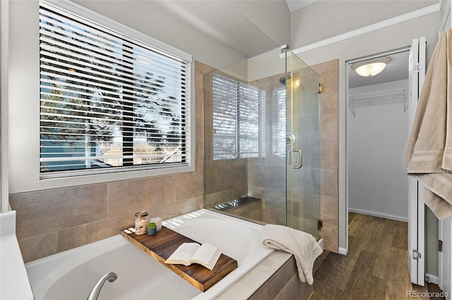 full bath featuring a bath, a stall shower, a walk in closet, and wood finished floors