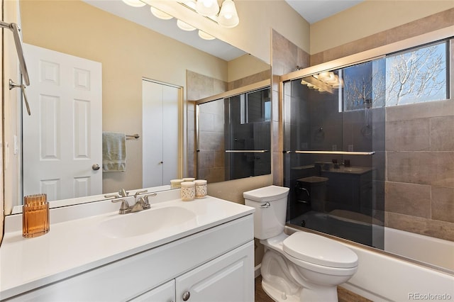 bathroom with shower / bath combination with glass door, vanity, and toilet