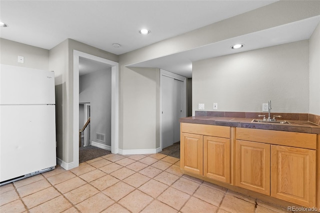 kitchen featuring dark countertops, visible vents, a sink, and freestanding refrigerator