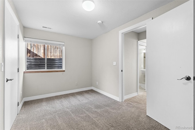 unfurnished bedroom with a textured ceiling, carpet, visible vents, and baseboards