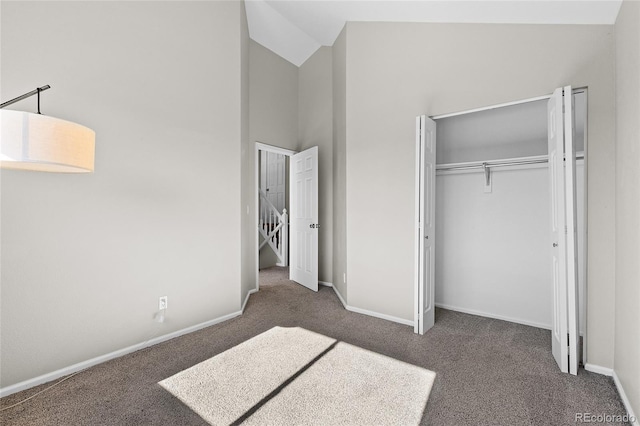 unfurnished bedroom with high vaulted ceiling, carpet, a closet, and baseboards