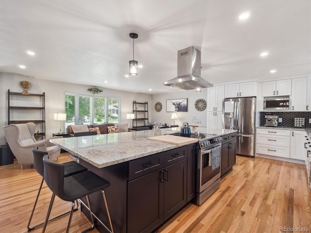 7379 S Lafayette Cir W, Centennial, CO 80122 - kitchen with stainless steel appliances, island exhaust hood, white cabinets, a center island, and light stone countertops