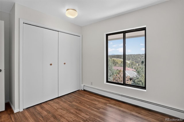 31270 John Wallace Rd Unit 302, Evergreen, CO 80439 - unfurnished bedroom featuring a baseboard radiator, a closet, and dark wood-style flooring