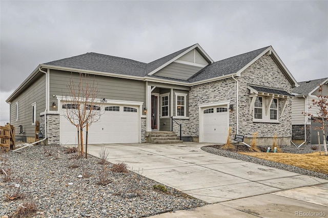 view of front of home with concrete driveway, an attached garage, stone siding, and a shingled roof