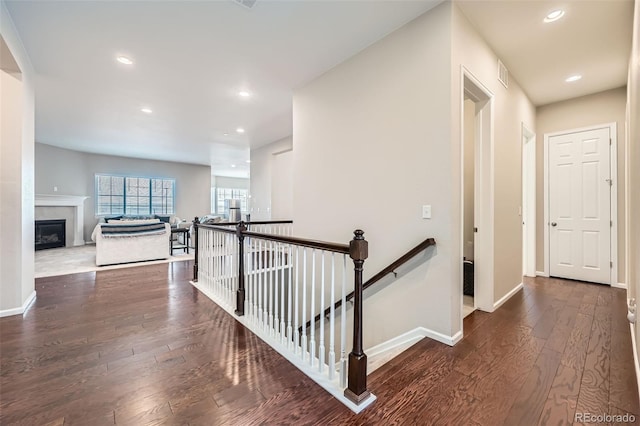 hallway featuring hardwood / wood-style floors, recessed lighting, an upstairs landing, and baseboards