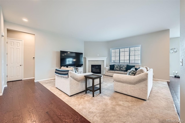 living room featuring a glass covered fireplace, baseboards, and wood finished floors