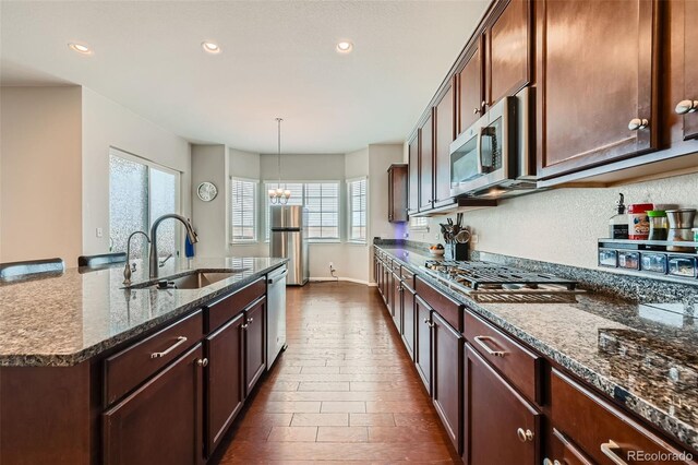 kitchen with a chandelier, dark stone countertops, plenty of natural light, stainless steel appliances, and a sink