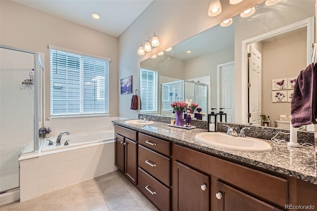 full bathroom featuring double vanity, a bath, a stall shower, and a sink