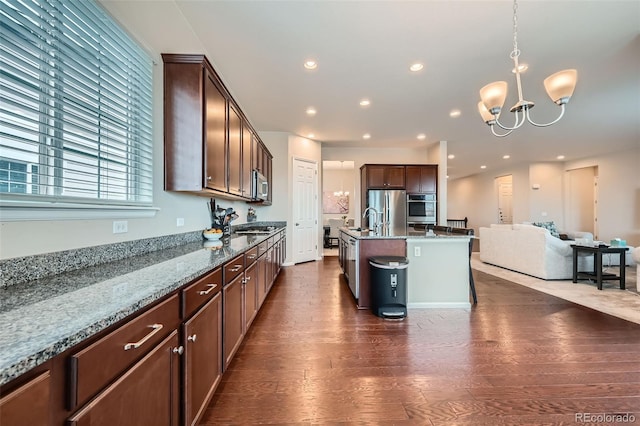 3630 Gold Bug St, Aurora, CO 80019 - kitchen with stainless steel appliances, a sink, dark wood-style flooring, open floor plan, and a notable chandelier