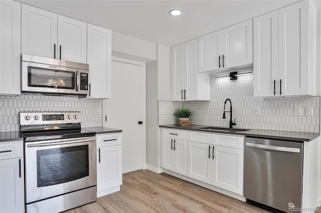 3575 S Ouray St, Aurora, CO 80013 - kitchen with stainless steel appliances, a sink, dark countertops, decorative backsplash, and white cabinets