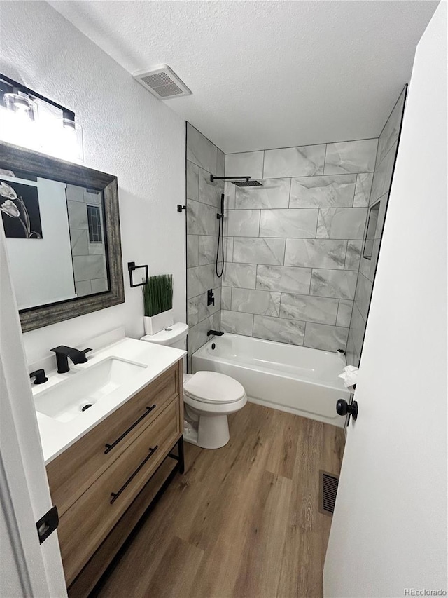 3575 S Ouray St, Aurora, CO 80013 - bathroom with wood finished floors, toilet, vanity, shower / washtub combination, and a textured ceiling