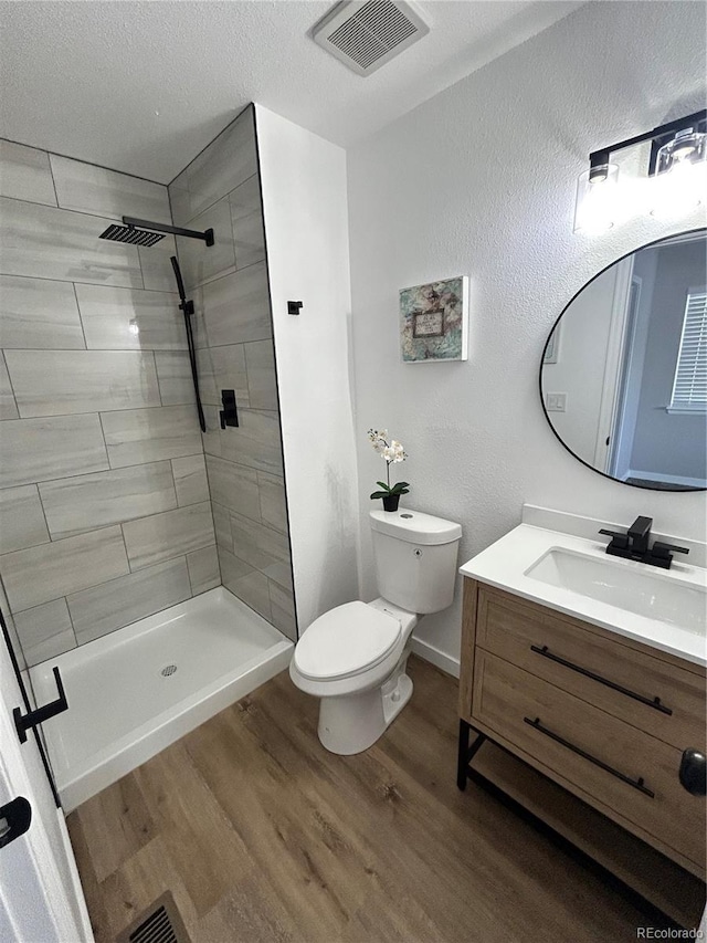 3575 S Ouray St, Aurora, CO 80013 - full bathroom with toilet, vanity, wood finished floors, tiled shower, and a textured ceiling