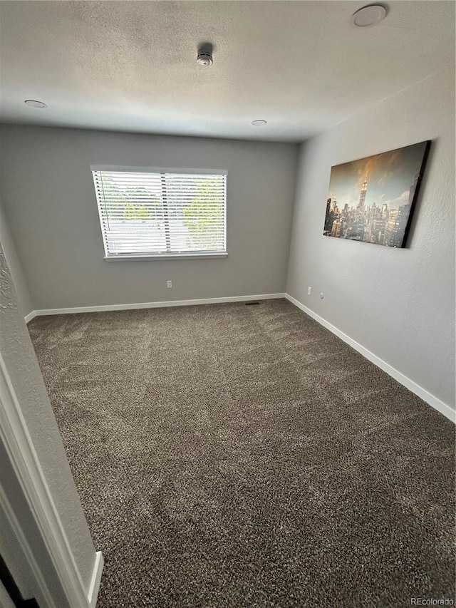3575 S Ouray St, Aurora, CO 80013 - empty room featuring baseboards, dark colored carpet, and a smoke detector