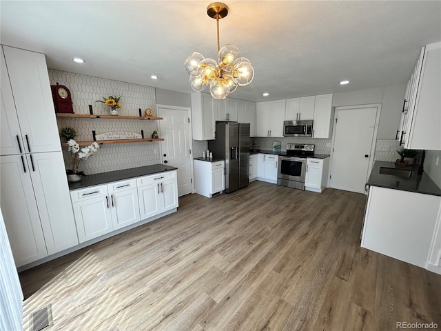 3575 S Ouray St, Aurora, CO 80013 - kitchen with stainless steel appliances, dark countertops, a chandelier, white cabinets, and tasteful backsplash