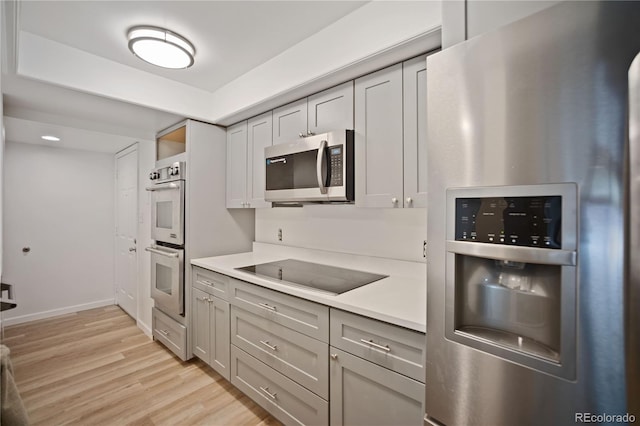 kitchen with light wood-type flooring, gray cabinets, stainless steel appliances, and light countertops