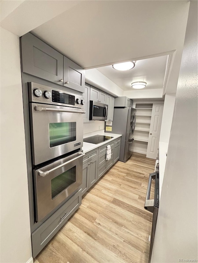 kitchen featuring light wood-style floors, gray cabinets, stainless steel appliances, and light countertops