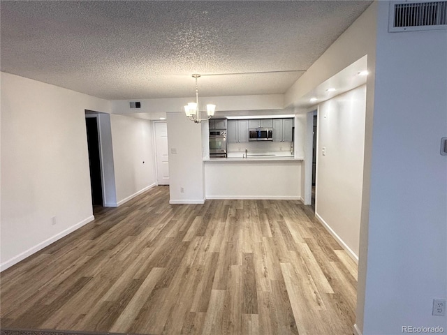 unfurnished living room with wood-type flooring, a textured ceiling, and a chandelier