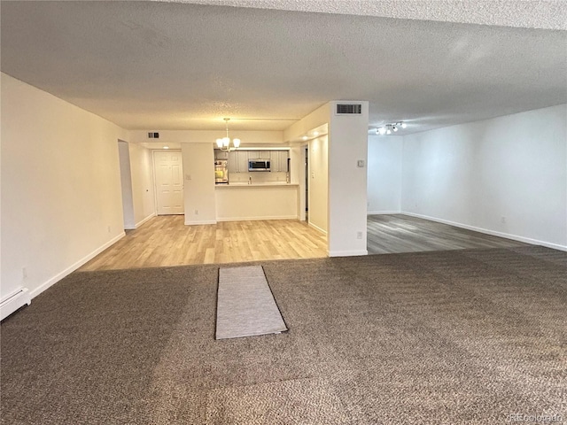 unfurnished living room featuring hardwood / wood-style floors, a notable chandelier, and a textured ceiling