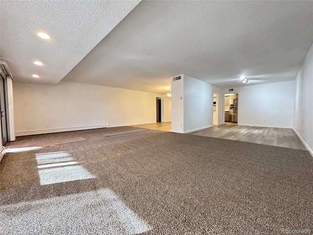 spare room with carpet flooring, a textured ceiling, and a baseboard radiator