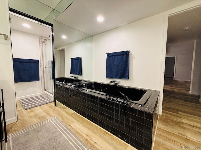 bathroom with separate shower and tub and wood-type flooring