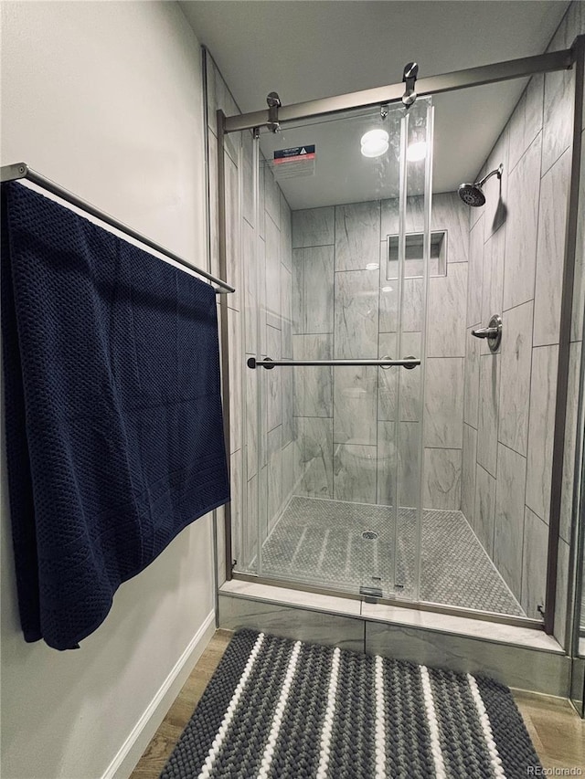 bathroom featuring wood-type flooring and a shower with shower door