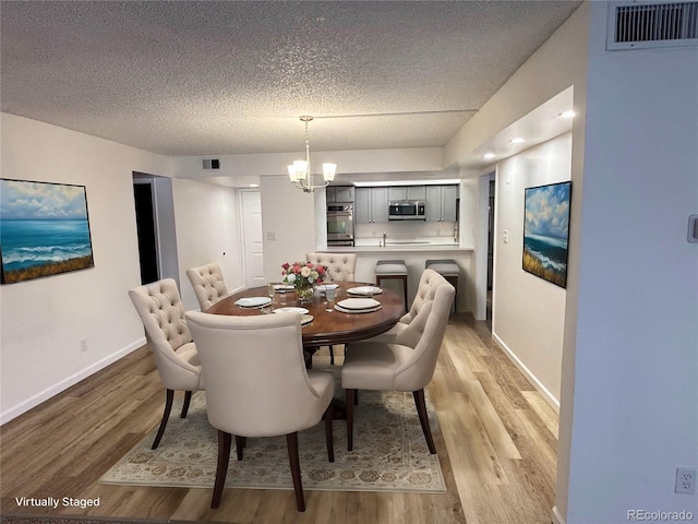 dining space featuring a notable chandelier, visible vents, and light wood-style floors