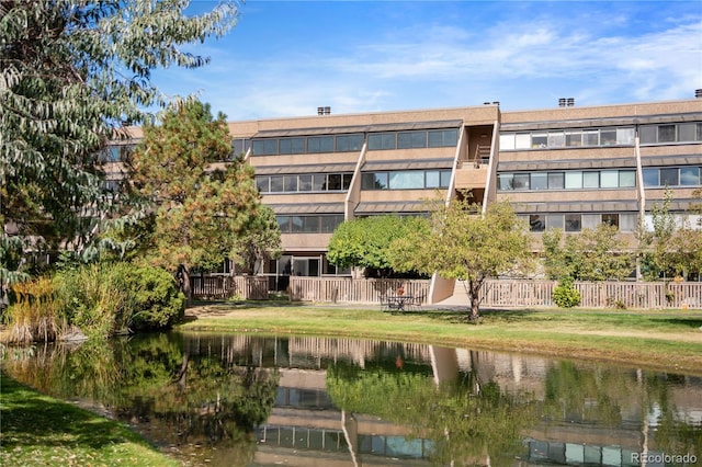 view of building exterior with a water view and fence