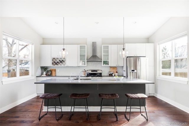 kitchen featuring wall chimney exhaust hood, appliances with stainless steel finishes, a breakfast bar area, and decorative backsplash