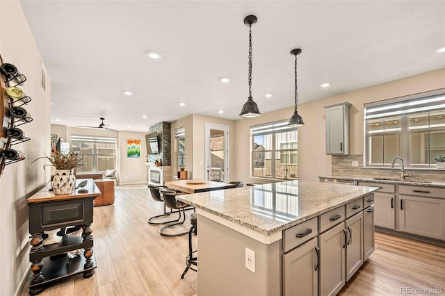 kitchen featuring backsplash, light wood-type flooring, a center island, and gray cabinetry