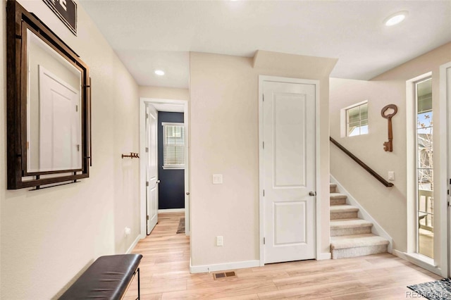 hallway featuring baseboards, visible vents, light wood-style flooring, stairs, and recessed lighting