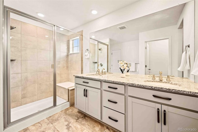 bathroom with double vanity, a stall shower, visible vents, and a sink