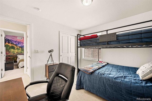 carpeted bedroom with visible vents and a closet