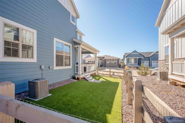 view of yard with central air condition unit, a residential view, and fence