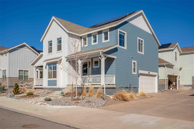 modern inspired farmhouse featuring covered porch, solar panels, a garage, decorative driveway, and board and batten siding