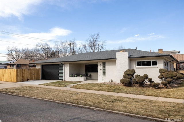 view of front of property featuring brick siding, a chimney, fence, a garage, and driveway