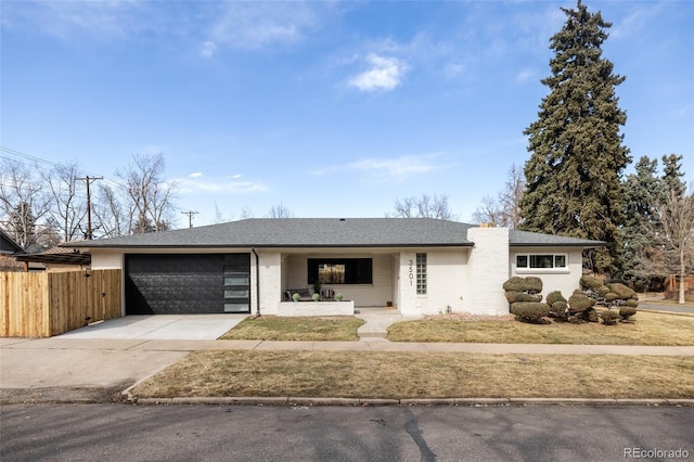 view of front of property featuring a garage, concrete driveway, fence, and a shingled roof