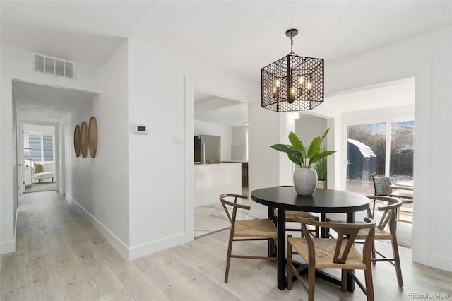 dining room featuring a notable chandelier, a wealth of natural light, and light hardwood / wood-style flooring