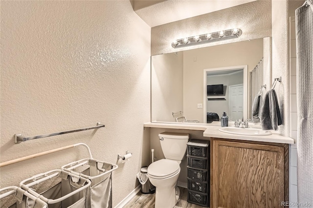 16320 E Fremont Ave Unit 1, Aurora, CO 80016 - bathroom with a textured wall, toilet, vanity, wood finished floors, and baseboards