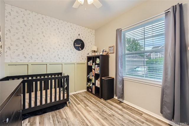 16320 E Fremont Ave Unit 1, Aurora, CO 80016 - bedroom featuring wallpapered walls, multiple windows, wood finished floors, wainscoting, and a crib